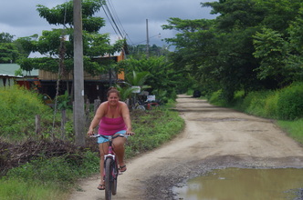 Picture of a host mother riding her bike down a puddle-filled road